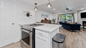 Une cuisine moderne avec un îlot central, un coin repas avec un canapé et une cheminée.