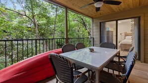 Un balcon abrité avec une table à manger, des chaises et un canapé rouge.