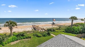 A beach view with a wooden deck, a flag, and a palm tree. - Carpe Beachiem Home, Ocean Views & Dual Decks (Ponte Vedra Beach)