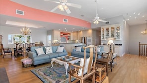 A spacious living room with a large sofa, a coffee table, and a dining area with chairs.