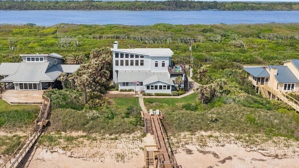A large, modern house with multiple levels, a dock, and a view of the ocean.