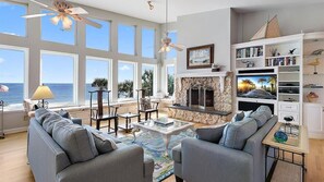 A spacious living room with a fireplace, large windows, and a view of the ocean. - Carpe Beachiem Home, Ocean Views & Dual Decks (Ponte Vedra Beach)