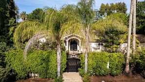 A house with a central archway, surrounded by lush greenery and palm trees. - 🌴Spacious & Private 5Bdr Private Retreat-Saltwater Pool/Spa, Outdoor Kitchen🌴 (Los Angeles)