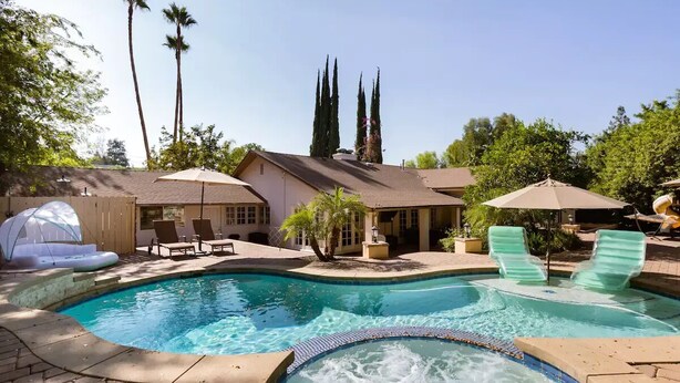 A swimming pool with lounge chairs and a hot tub, surrounded by palm trees and a house. - 🌴Spacious & Private 5Bdr Private Retreat-Saltwater Pool/Spa, Outdoor Kitchen🌴 (Los Angeles)