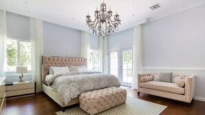 A spacious bedroom with a large bed, a tufted bench, a sofa, and a chandelier. - 🌴Spacious & Private 5Bdr Private Retreat-Saltwater Pool/Spa, Outdoor Kitchen🌴 (Los Angeles)