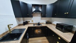 A compact kitchen with dark cabinets, a wooden countertop, a sink, a microwave, and a stove. - Best Location in Belfast! Free Parking-Luxury Accommodation (Belfast)