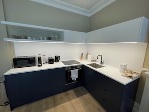 A modern kitchen with a built-in oven, microwave, coffee maker, and a sink. - Chic 1BD City Stay in the Heart of London (London)