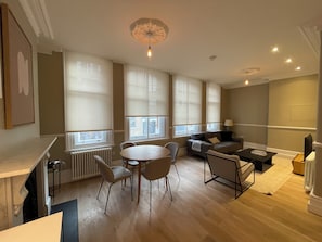 A modern living room with a round table and chairs, a sofa, and a TV. - Chic 1BD City Stay in the Heart of London (London)