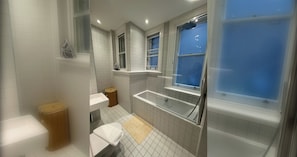 A bathroom with a bathtub, a sink, and a window. - Chic 1BD City Stay in the Heart of London (London)