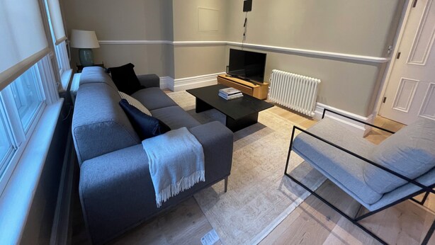 Una sala moderna con un conjunto de sofá, una mesa de centro, un televisor y un radiador.