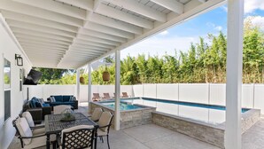 A covered patio with a pool, outdoor seating, and a grill area. - Beach Chickens is your vacation destination for Pool Side Relaxation (St. Simons Island)