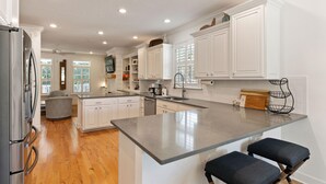 A modern kitchen with white cabinetry, a granite countertop, and a built-in oven. - Beach Chickens is your vacation destination for Pool Side Relaxation (St. Simons Island)