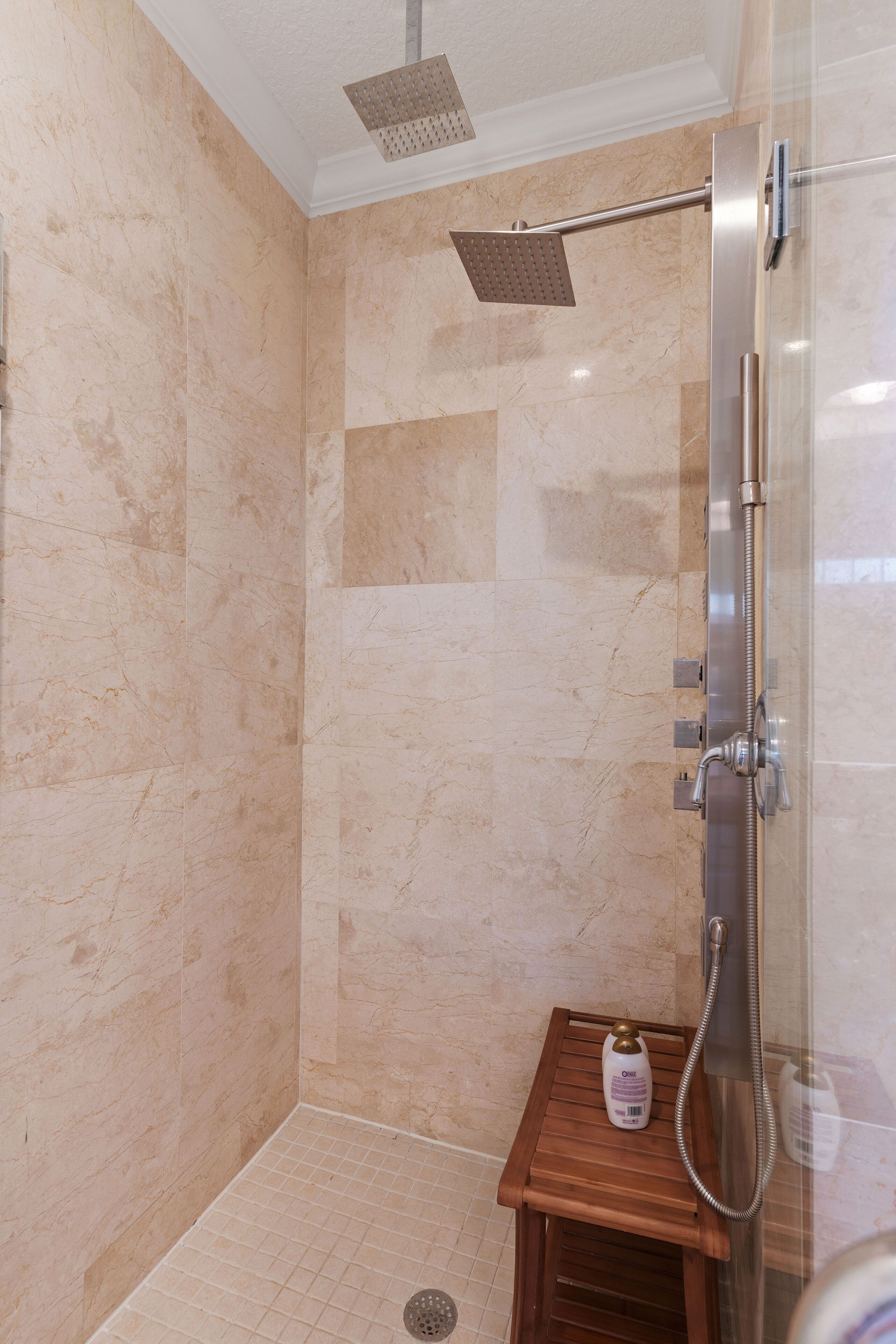 A shower with a handheld showerhead and a square showerhead mounted on the ceiling.