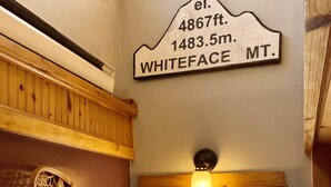 Eine Holzwand mit einem Schild, das die Höhe des Whiteface Mountain angibt, und ein Fenster mit Blick auf eine verschneite Landschaft.