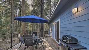 A deck with a table, chairs, a grill, and a blue umbrella. - Secluded Butte Meadows Cabin w/ Deck & Grill! (Butte Meadows)