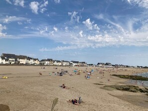 A beach with houses in the background and people sunbathing.