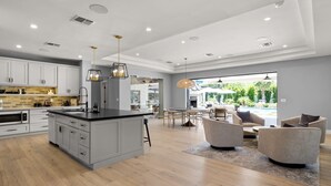 A modern kitchen with grey cabinets, a central island, and pendant lighting. - Multi-Million $ Resort-Style Estate w/Pickleball (Scottsdale)