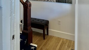 Un escalier menant à un palier où se trouvent un banc et un luminaire fixé au mur.