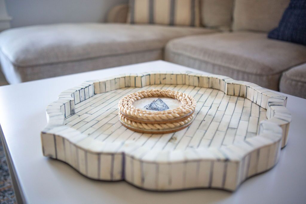 Ein runder, weißer Holztisch mit einem geflochtenen Rope-Mittelstück und einem kleinen, pyramidenförmigen Objekt darauf.