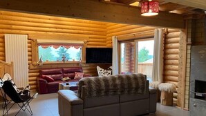 En stuga byggd av timmer med en soffa, en fåtölj och en öppen spis.