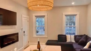 Un salon moderne doté d’un grand téléviseur, d’une cheminée et d’un coin repas avec une table et des chaises.