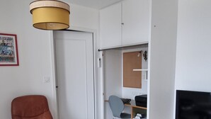 Una sala de estar con un sofá de cuero marrón, una mesa de centro de madera, un televisor sobre un mueble de madera y una lámpara en el techo.
