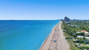 A coastal beach with a clear view of the ocean and a cityscape in the background.