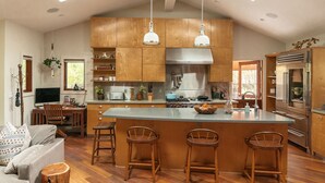 Una cocina amplia con armarios de madera, una isla grande con taburetes y electrodomésticos modernos.