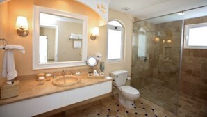 Un baño con un espejo grande, un lavamanos, un inodoro y una ducha con mampara de vidrio.