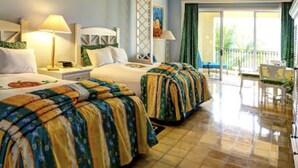 Habitación de hotel con dos camas, un balcón y zona de comedor.