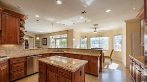 A spacious kitchen with granite countertops, wooden cabinets, and a large island. - Large Luxurious Estate on Golf Course w/pool/spa in Gated Community (Henderson)