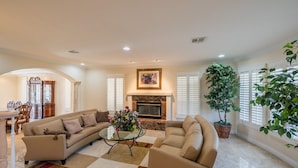 A spacious living room with a fireplace, comfortable seating, and large windows. - Large Luxurious Estate on Golf Course w/pool/spa in Gated Community (Henderson)