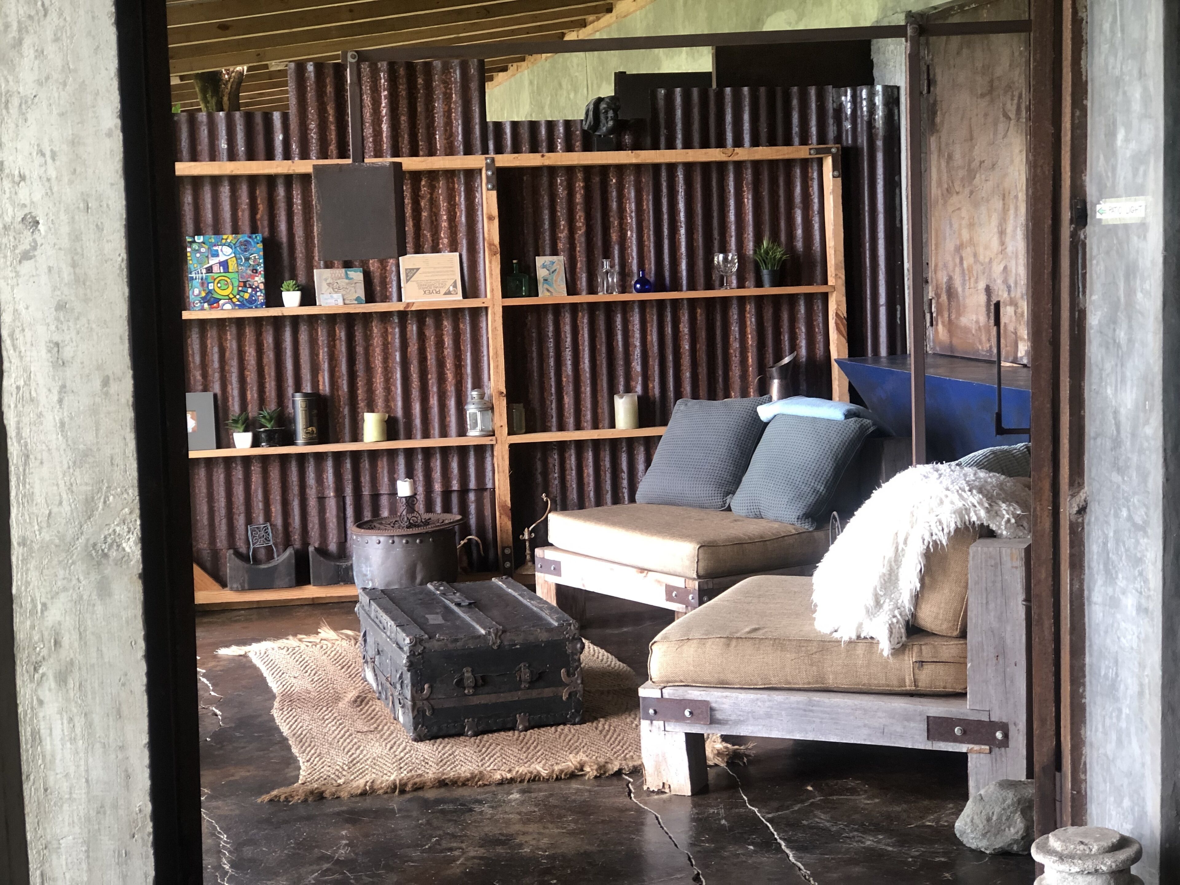 A rustic interior with a sofa, a wooden bookshelf, and a vintage suitcase.