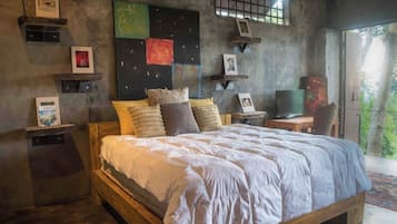 A bedroom with a wooden bed, multiple pillows, a television, and artwork on the walls.