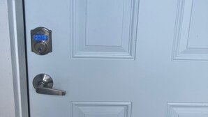 Una puerta blanca con cerradura electrónica y manija.
