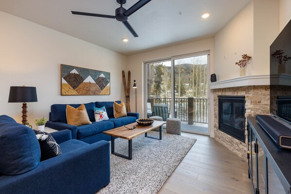 A modern living room with a blue sofa set, a wooden coffee table, and a fireplace.
