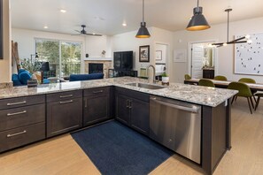 A modern kitchen with dark cabinetry, granite countertops, and stainless steel appliances.