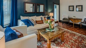 A living room with a sofa, armchairs, a coffee table, and a patterned rug.