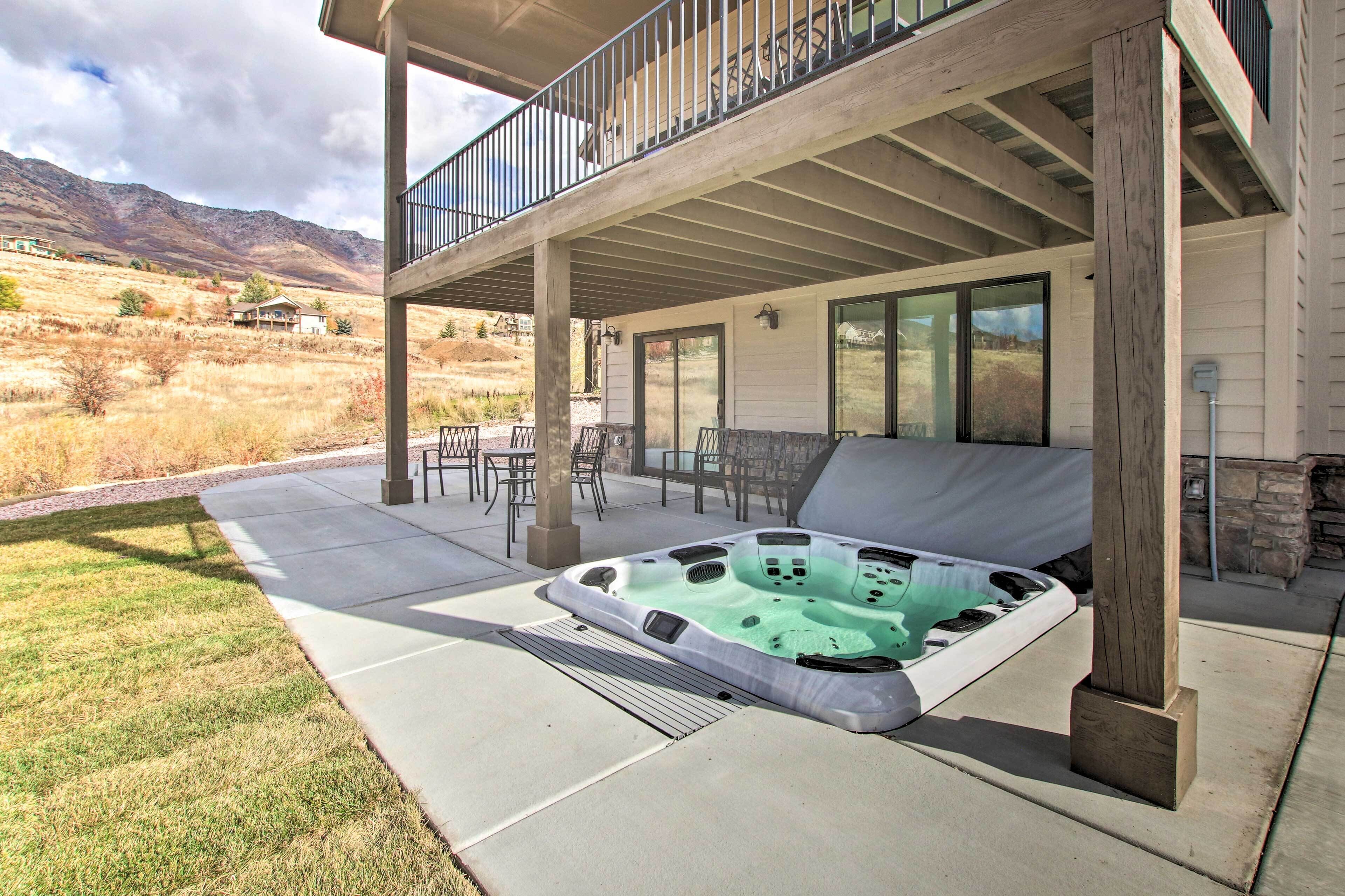 Un patio techado con un jacuzzi, mobiliario exterior y vistas del paisaje circundante.