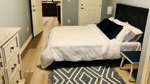 A bedroom with a bed, dresser, and a view into the bathroom. - Olympic Views - Cozy Modern 2BR Suite (Victoria)