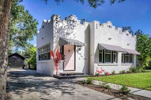 A castle-like building with a white facade, large windows, and a small porch with a striped awning.