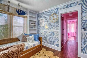 A bedroom with a wooden bed, a wall with wave patterns, and a pink door leading to another room. - Retro FL Charm | Pool + Spa | AMI + Downtown | IMG (Bradenton)