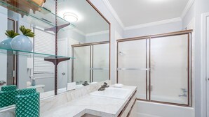 A modern bathroom with a double sink vanity, a large mirror, and a glass shower enclosure. - Beautiful, Remodeled Penthouse Unit in Old Town! (Chicago)