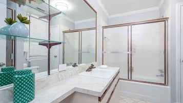 A modern bathroom with a double sink vanity, a large mirror, and a glass shower enclosure.