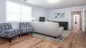 A living room with a grey sofa, patterned armchairs, a black sofa, and a TV. - Beautiful, Remodeled Penthouse Unit in Old Town! (Chicago)