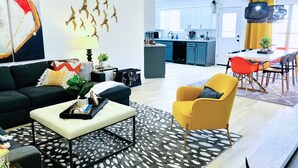 Una sala de estar moderna con un sofá, un sillón, una mesa de centro y un comedor con sillas y una mesa.