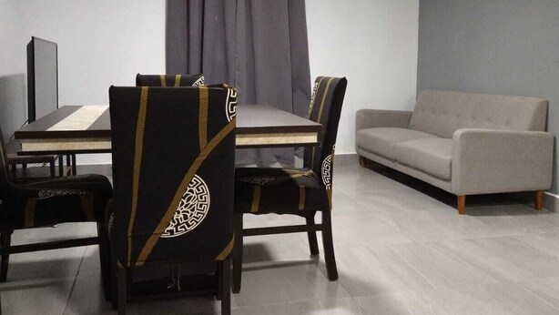 Een eethoek met een tafel en stoelen, een bank en een raam met gordijnen.