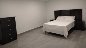 Een slaapkamer met een bed, een kaptafel en een nachtkastje.