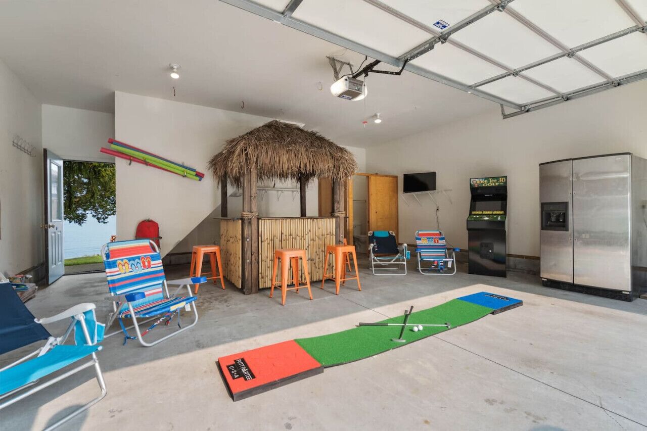 A room with a thatched roof, a pool table, and a bar area with stools.