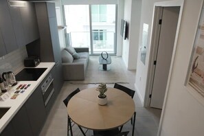 A modern kitchen with a dining area, a sofa, and a small table with a plant. - Lovely studio unit in Miami-Van Dennis (Miami)